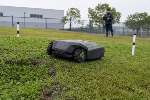 Autonomous robotic lawn mower undergoing lithium battery reliability testing on damp uneven terrain