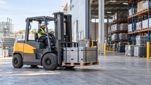 Heavy-duty electric forklift transporting an industrial load outside a warehouse